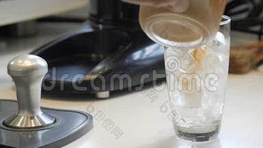 咖啡师在一杯冰中倒入新鲜咖啡